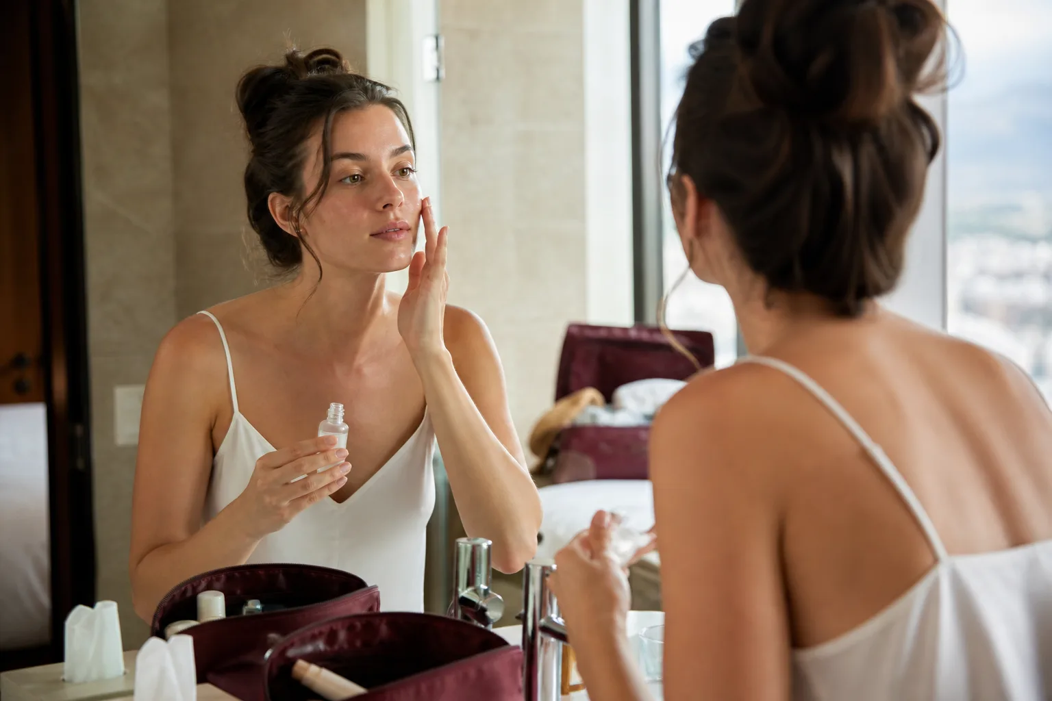 Woman applying serum in a hotel bathroom after a flight